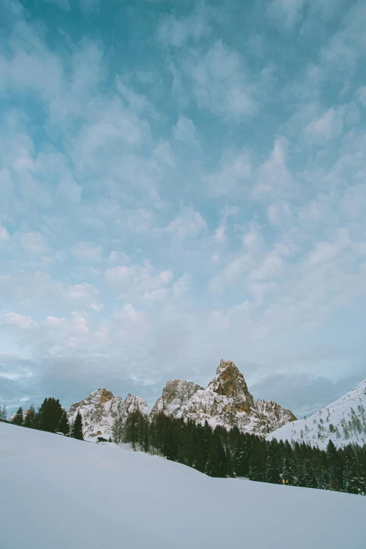 a man riding skis down a snow covered slope, by Carlo Martini, unsplash contest winner, romanticism, tall stone spires, puffy clouds, panoramic, cozy