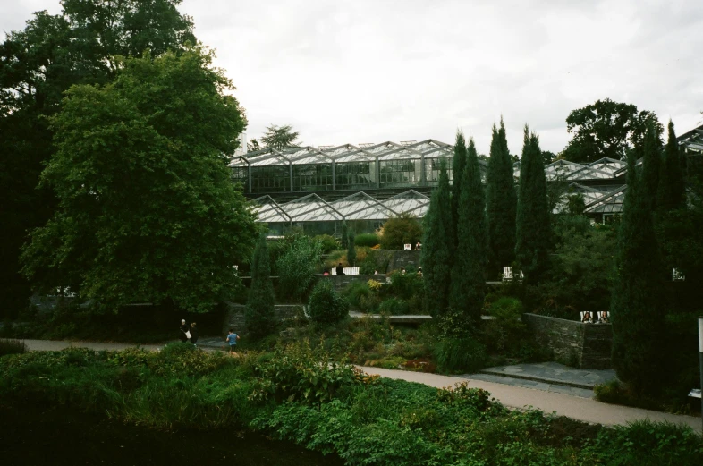 a building with a glass roof next to a body of water, an album cover, inspired by Thomas Struth, unsplash, botanic garden, bath, grey, garden road