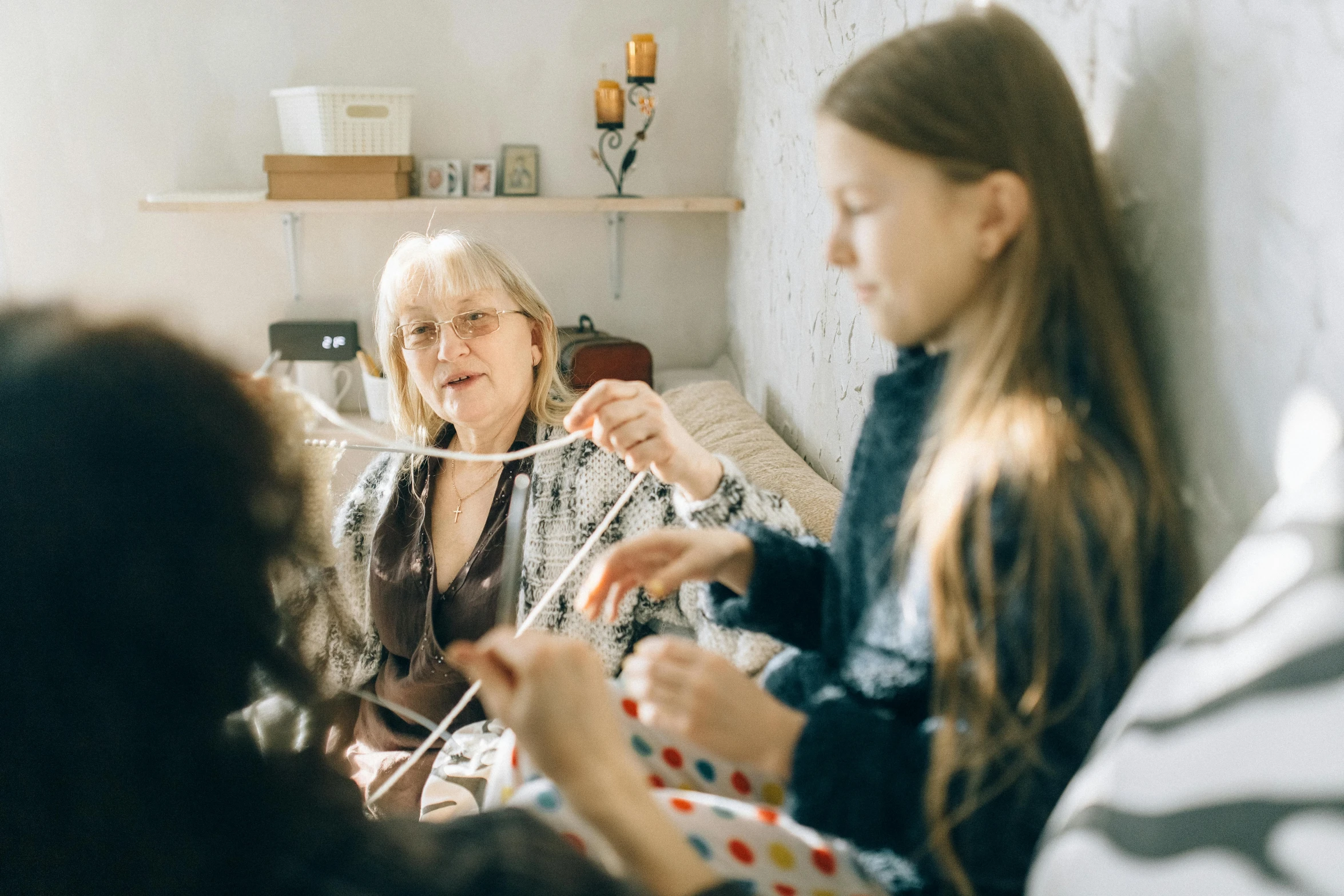 a group of women sitting on top of a bed, a cross stitch, pexels contest winner, grandma, weaving, teenage girl, cardboard