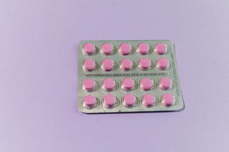 pink pills in a blister pack on a purple background, by Rachel Reckitt, pexels, antipodeans, on a gray background, sitting on top a table, panels, very round