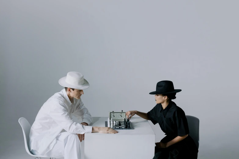 two people sitting at a table playing chess, an album cover, by Marina Abramović, unsplash contest winner, bauhaus, white suit and hat, ignant, tokujin yoshioka, futuristic nft card game