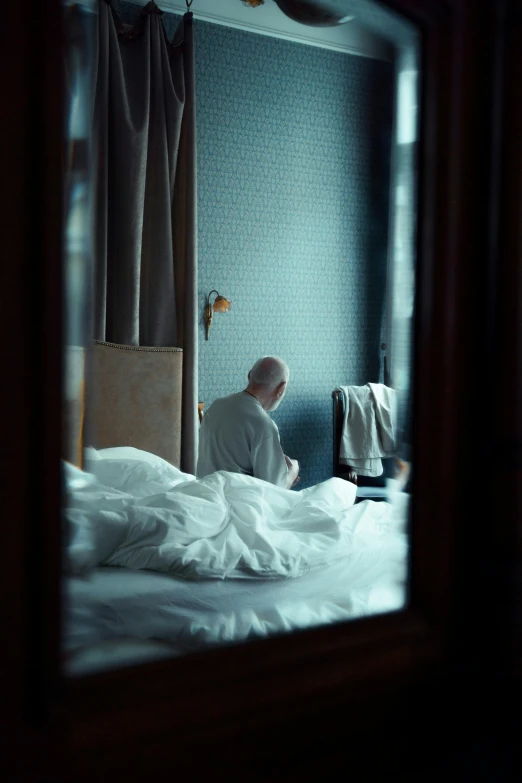 a man sitting on a bed in a dark room, a photo, by Elsa Bleda, unsplash, hyperrealism, looking in mirror at older self, hotel room, pierre pellegrini and ash thorp, with his back turned