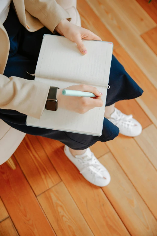 a person sitting on a chair with a notebook and pen, wearing white sneakers, sakimichan, sitting with wrists together, school curriculum expert