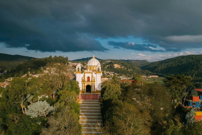 a large white building sitting on top of a lush green hillside, by Alejandro Obregón, unsplash contest winner, hindu temple in background, mexican, vallejo, mustard