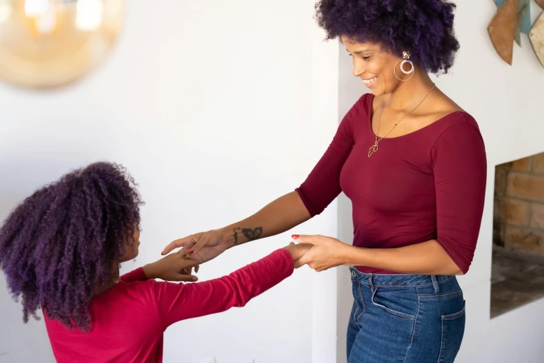 a woman standing next to a little girl in a room, pexels contest winner, black arts movement, holding each other hands, red and purple, tapping in to something greater, sleek hands