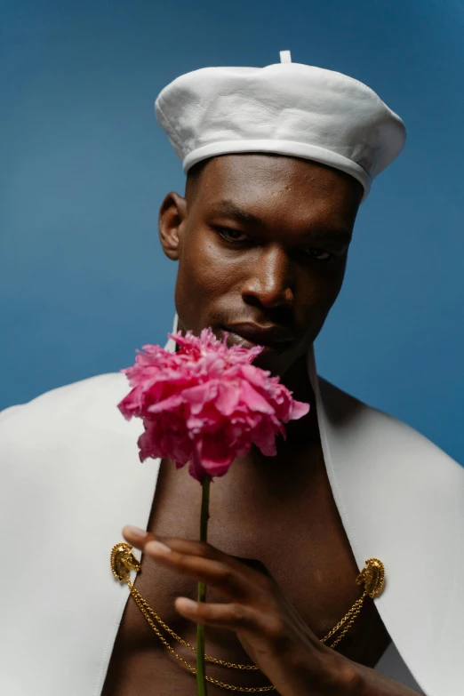 a close up of a person holding a flower, an album cover, inspired by Barthélemy Menn, male model, wearing white chef hat, dark skinned, lgbtq