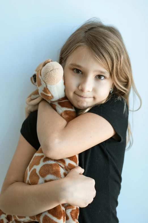 a little girl holding a stuffed giraffe in her arms, inspired by Sarah Lucas, unsplash, hugging each other, studio photo, concerned, foam