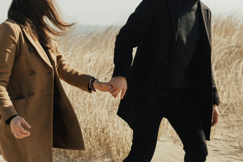 a man and a woman holding hands in a field, trending on pexels, wearing black overcoat, beaches, thumbnail, background image