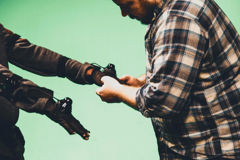 a couple of men standing next to each other, by Ryan Pancoast, unsplash, fantastic realism, robotic prosthetic arm, shooting a gun, weta fx, claymation style