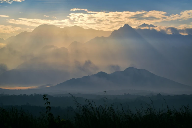 the sun shines through the clouds over the mountains, pexels contest winner, sumatraism, laos, foggy photo 8 k, multiple stories, view from the distance