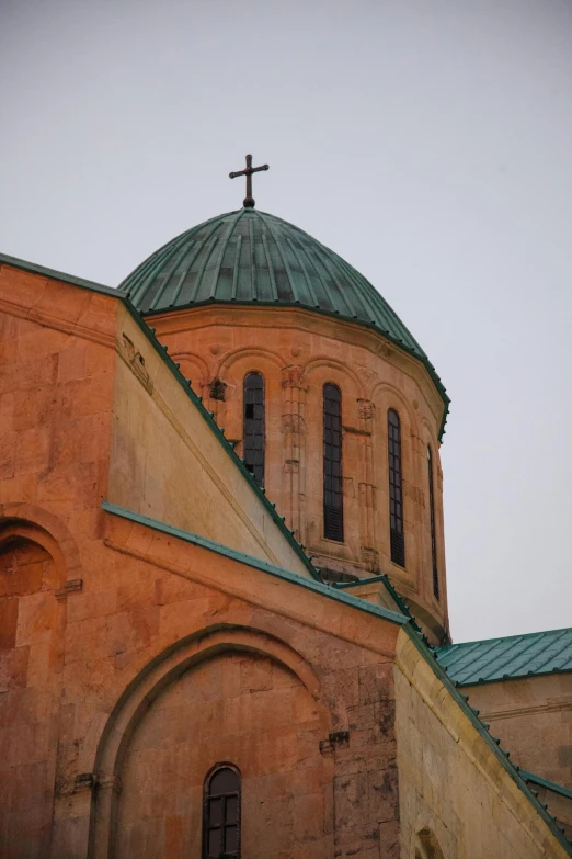 a church with a cross on top of it, inspired by Arthur Sarkissian, rounded roof, orange roof, green, up close