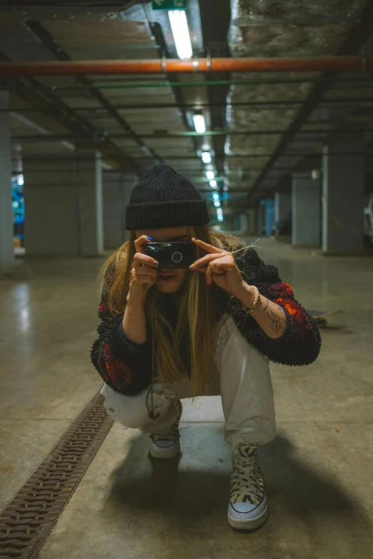 a woman taking a picture of herself in a parking garage, a picture, inspired by Elsa Bleda, unsplash contest winner, graffiti, badass pose, crouching, low quality photo, tomboy