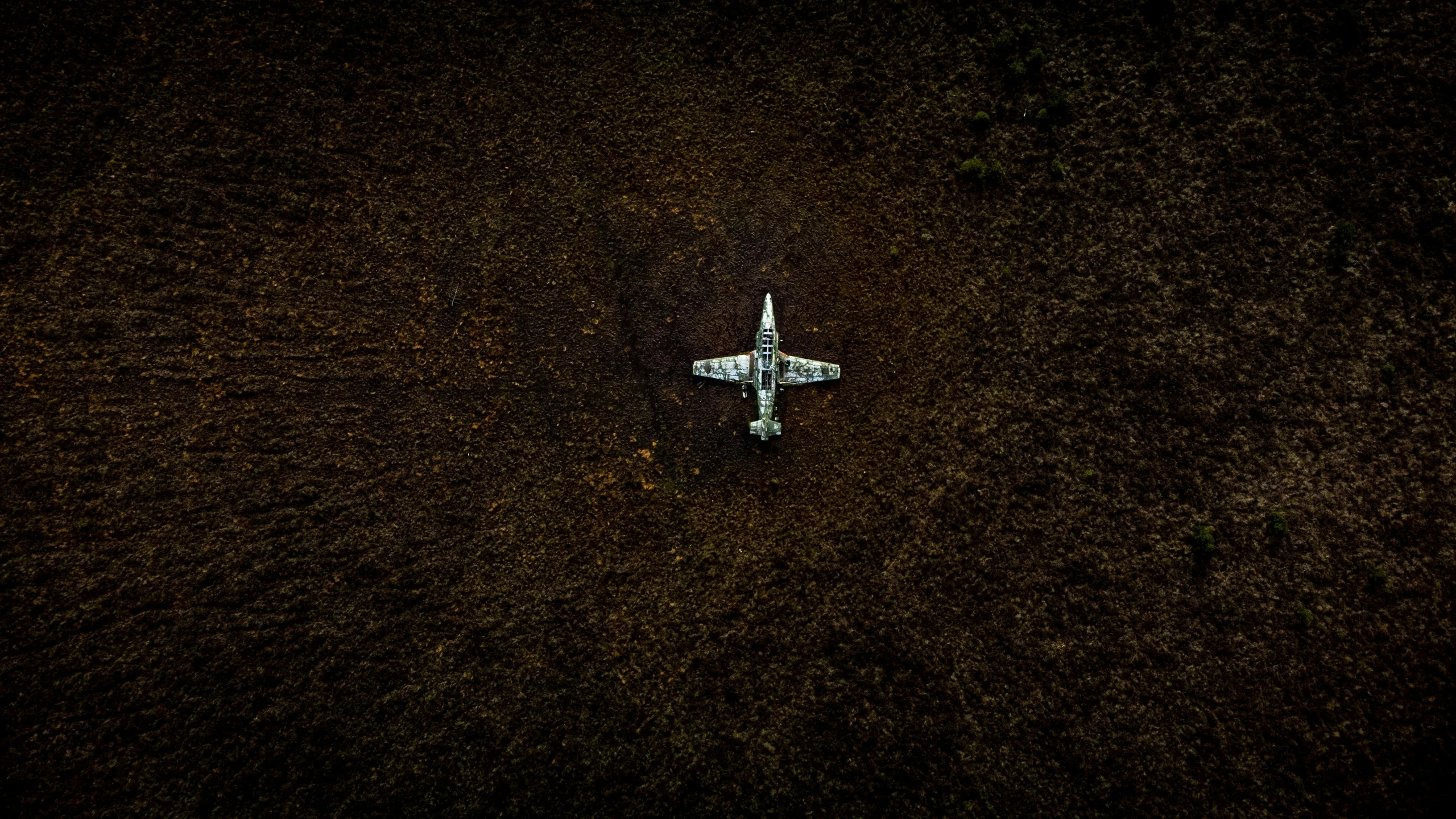 an airplane that is sitting in the dirt, by Elsa Bleda, unsplash contest winner, land art, military drone, sunken, out in the dark, no people 4k