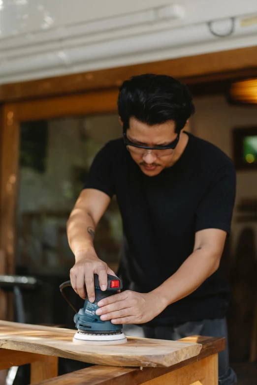 a man sanding a piece of wood with a sander, inspired by Hiroshi Honda, bartending, profile image, asian male, biker