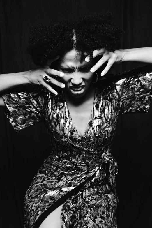 a black and white photo of a woman in a dress, hands shielding face, with afro, aggressive pose, 2010s