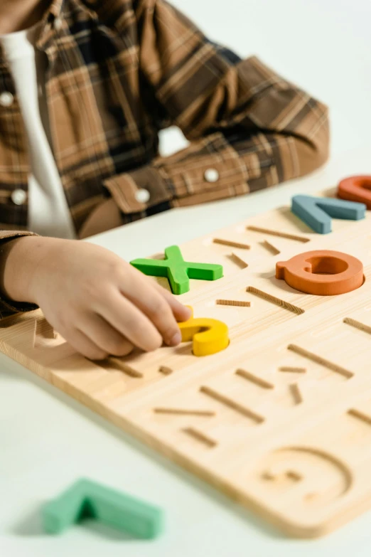 a little boy that is sitting at a table, a jigsaw puzzle, trending on pexels, geometric wood carvings, uppercase letter, mathematics, multi colour