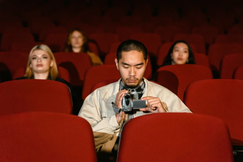 a man sitting in a theater holding a camera, pexels contest winner, hyperrealism, anime film still, [ theatrical ]