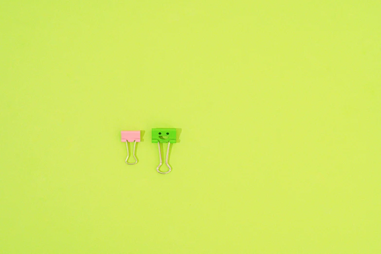 a couple of paper clips sitting on top of a green surface, pink and green colour palette, small smile, chartreuse color scheme, ffffound