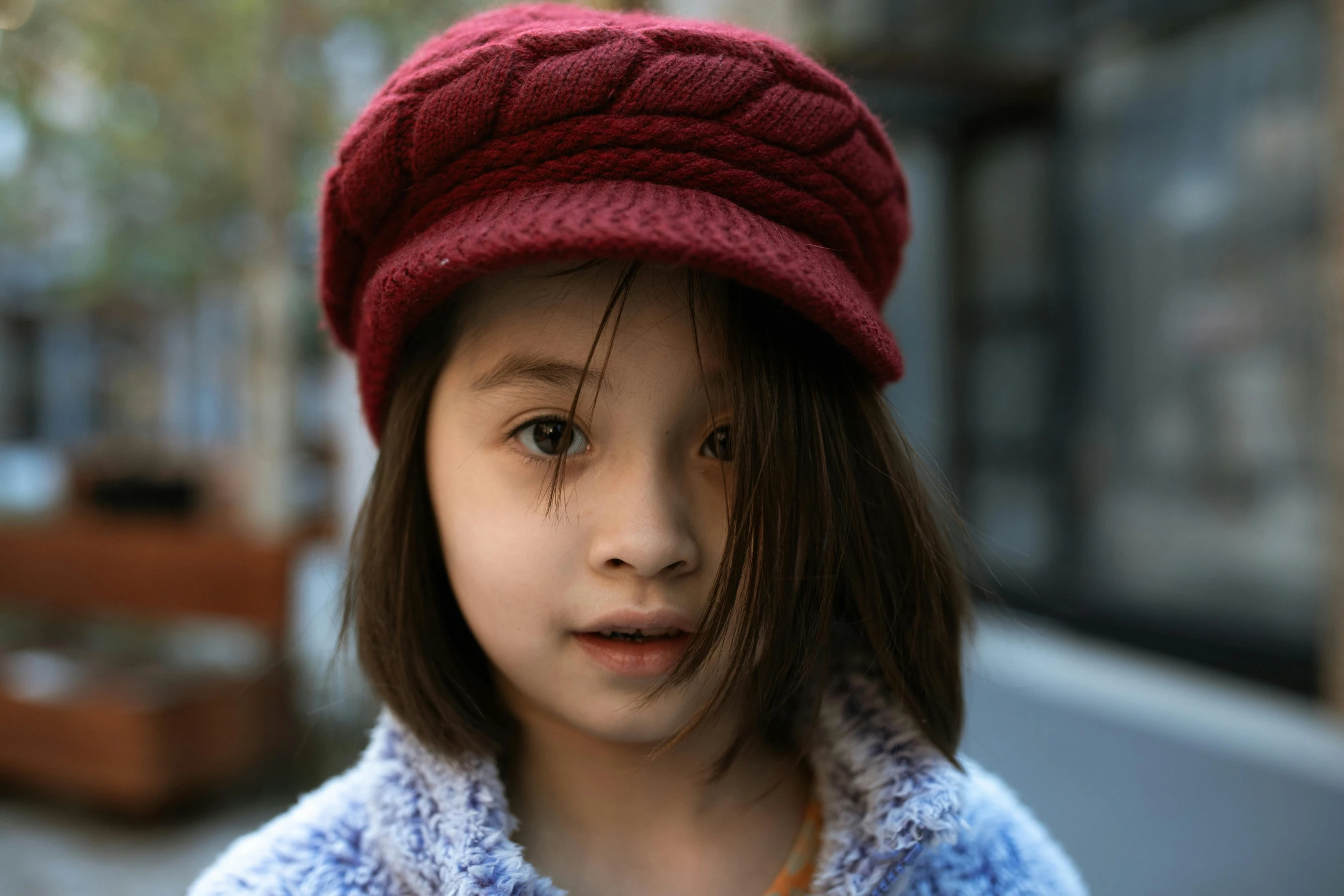 a close up of a child wearing a hat, maroon red, girl with plaits, berets, portrait featured on unsplash