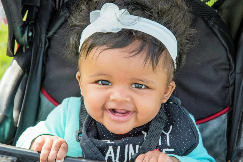 a close up of a baby in a stroller, by Washington Allston, pexels contest winner, happening, large black smile, zenra taliyah, mixed race, rectangle