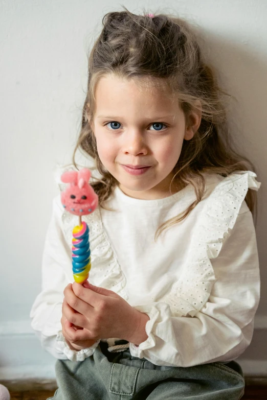 a little girl sitting on the floor holding a toothbrush, inspired by Sophie Anderson, candy worms, made out of sweets, peppa pig, product display photograph