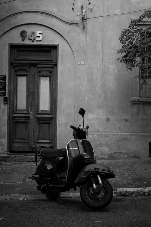 a black and white photo of a scooter parked in front of a building, a black and white photo, by Luca Zontini, 2 5 6 x 2 5 6, door, late summer evening, a small