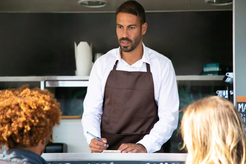 a man that is standing in front of a counter, serving suggestion, wearing a vest top, brown, camilo gc