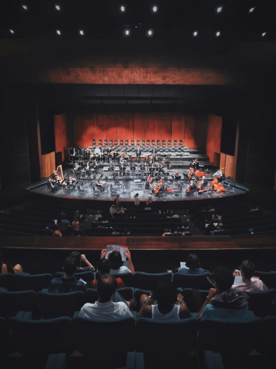 a group of people sitting in front of a stage, by Alejandro Obregón, unsplash contest winner, modernism, orchestra, full room view, in sao paulo, promo image