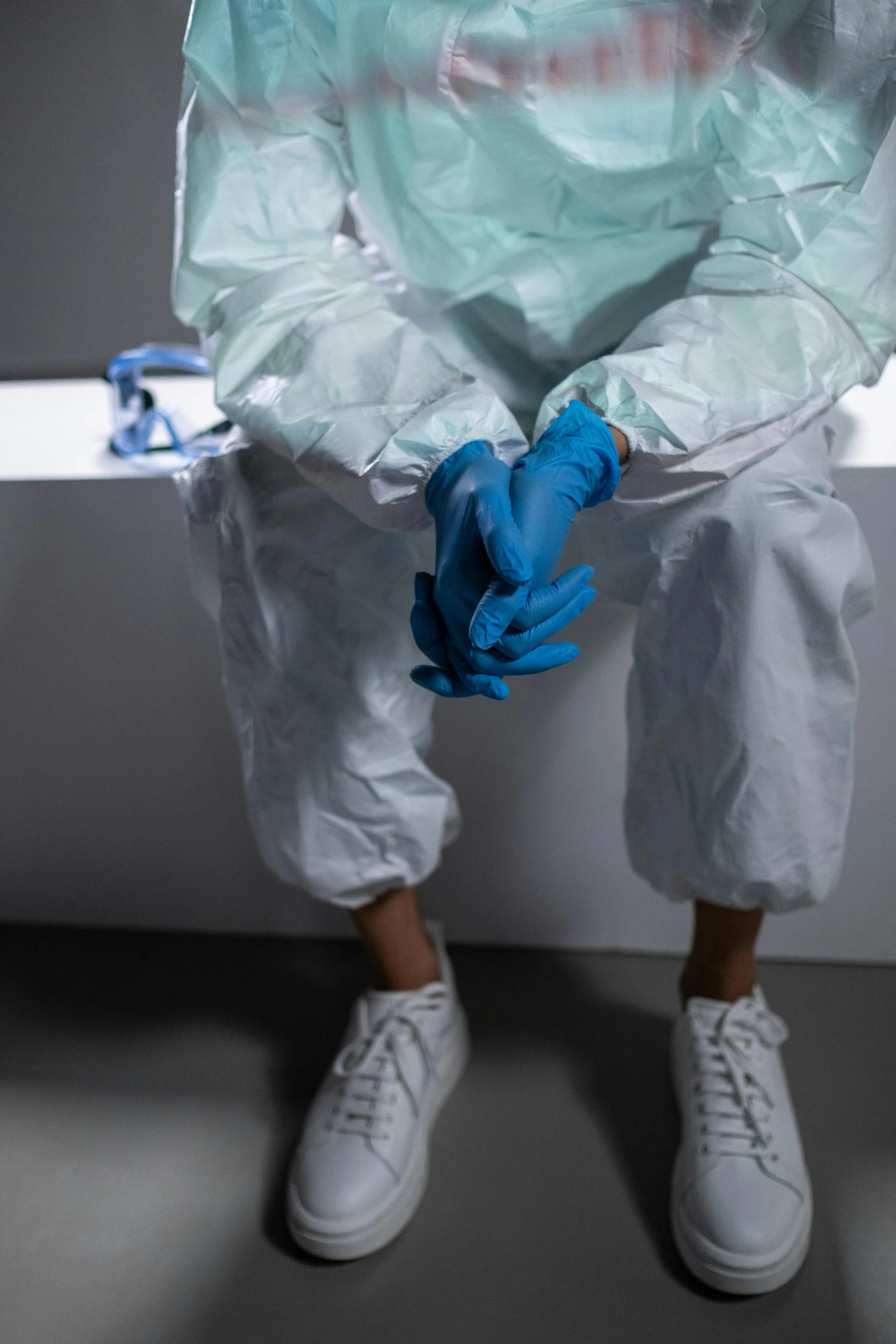 a man in a protective suit sitting on a window sill, trending on pexels, blue gloves, wearing a labcoat, photograph of a techwear woman, bench