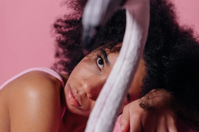 a woman laying on top of a bed next to a flamingo, trending on pexels, curly afro, exhausted face close up, holding a thick staff, sad look