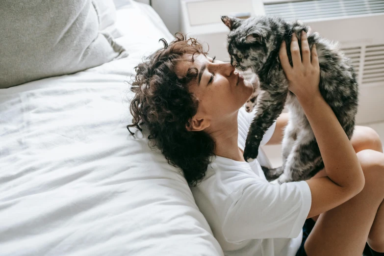 a woman laying in bed with a cat on her lap, pexels contest winner, curly haired, thumbnail, hugging each other, ad image