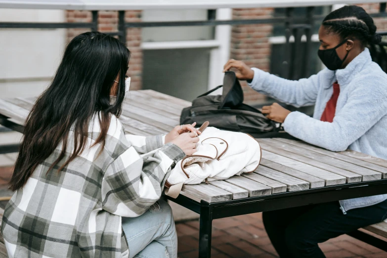 a couple of people that are sitting at a table, trending on pexels, bags on ground, black haired girl wearing hoodie, thumbnail, schools