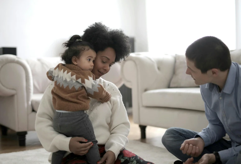 a man and woman sitting on the floor with a baby, lgbtq, brown and white color scheme, light skinned african young girl, multiple stories