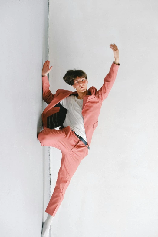 a man in a pink suit leaning against a wall, unsplash, gutai group, playful pose of a dancer, sophia lillis, nishihara isao, [ zero - gravity ]!!