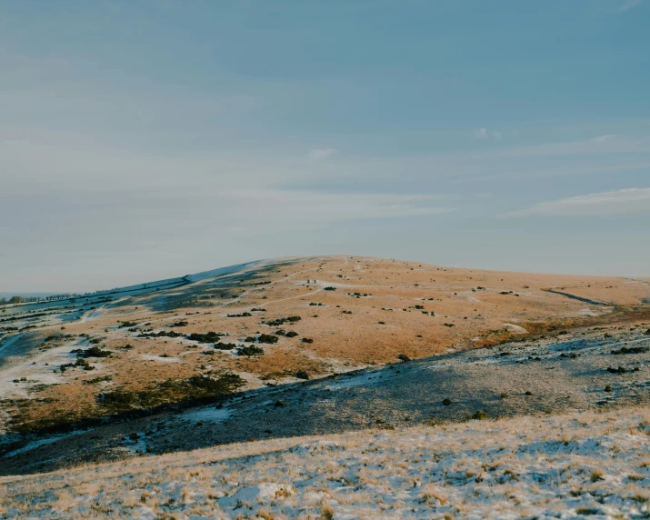 a man flying a kite on top of a snow covered hillside, by Emma Andijewska, unsplash contest winner, land art, brown stubble, background image, wales, distant - mid - shot