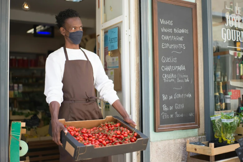 a man holding a box of strawberries in front of a store, pexels contest winner, renaissance, adut akech, white apron, portugal, wearing facemask