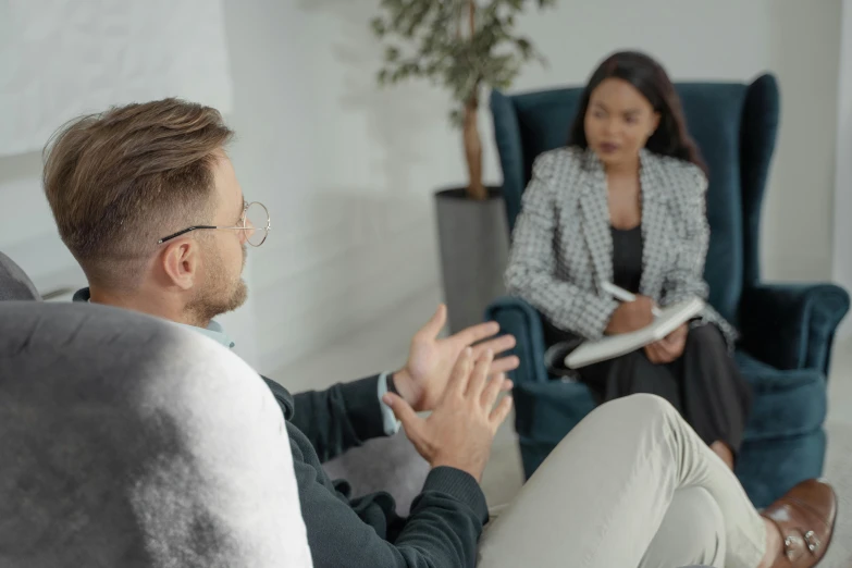 a man and woman sitting on a couch in a living room, court session images, mental health, low quality photo, local conspirologist