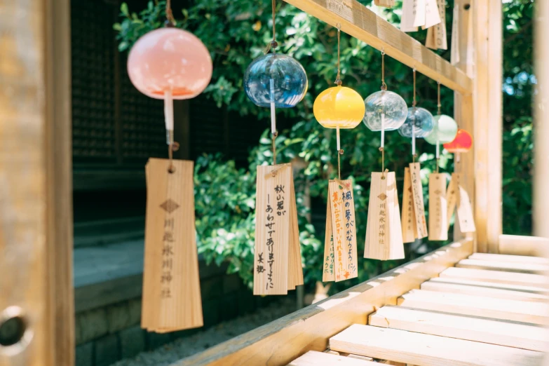 a bunch of tags hanging from the side of a window, inspired by Torii Kiyomoto, unsplash, sōsaku hanga, pagoda with a lot of wind chimes, sparkling in the sunlight, beautiful kawaii lighting, a wooden