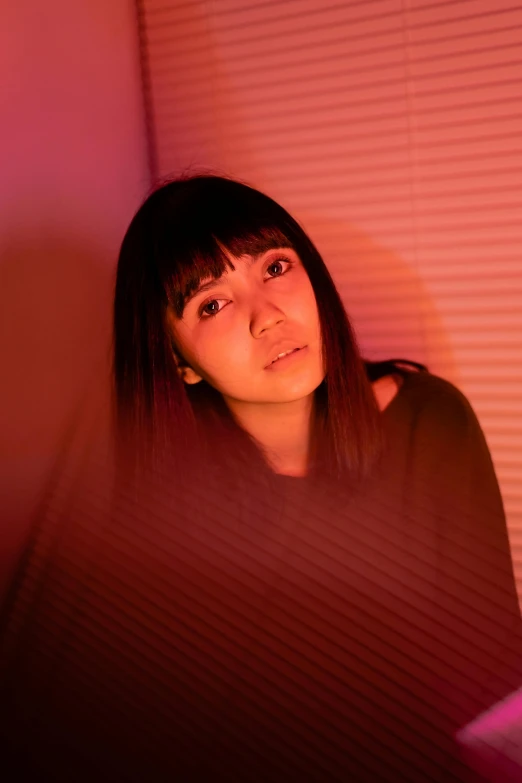 a woman sitting in front of a laptop computer, an album cover, inspired by Miwa Komatsu, unsplash, serious lighting, headshot, red lighting, sarah andersen