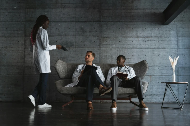 a couple of people that are sitting on a couch, by Emma Andijewska, pexels contest winner, wearing a labcoat, gray men, dark people discussing, full body portrait of a group