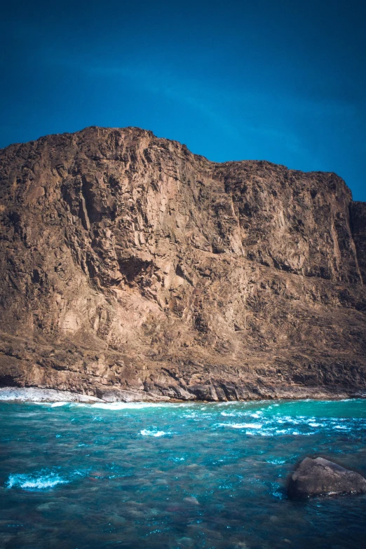 a large rock in the middle of a body of water, les nabis, in socotra island, rugged face, towering waves, brown