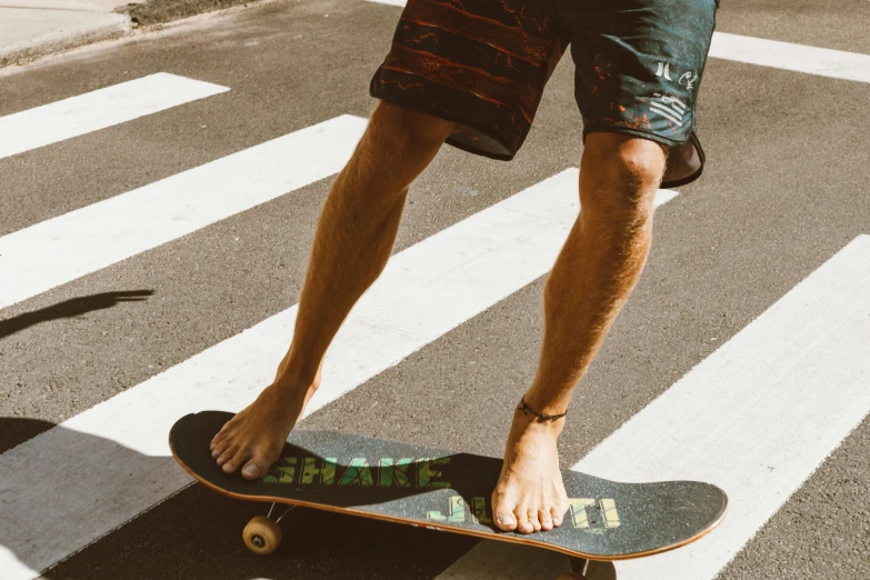 a man riding a skateboard across a crosswalk, pexels contest winner, flip flops, bare thighs, chalked, hand made