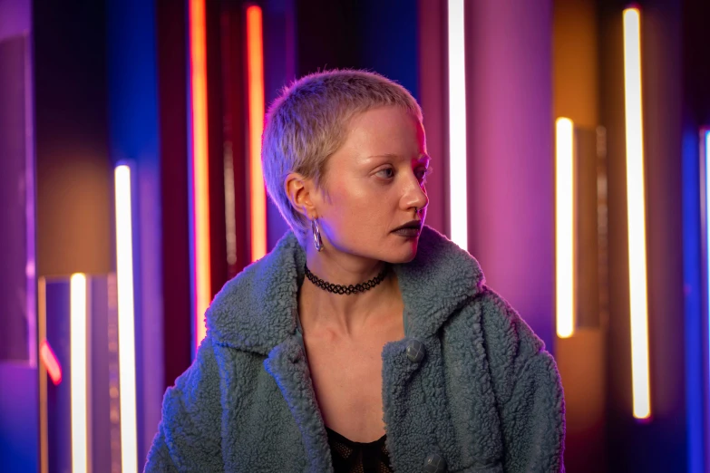 a woman standing in front of neon lights, inspired by Nan Goldin, pexels contest winner, bauhaus, shaved hair, brienne of tarth, melanchonic soft light, behind the scenes photo