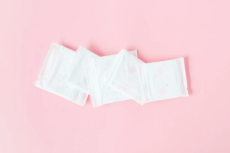 a pair of disposable sanitary pads on a pink background, in a row, jen atkin, white background, 80mm