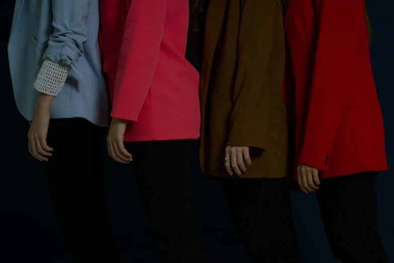 a group of women standing next to each other, by Matija Jama, trending on unsplash, bauhaus, wearing red jacket, on black background, pink and blue colour, loose - fitting blouses