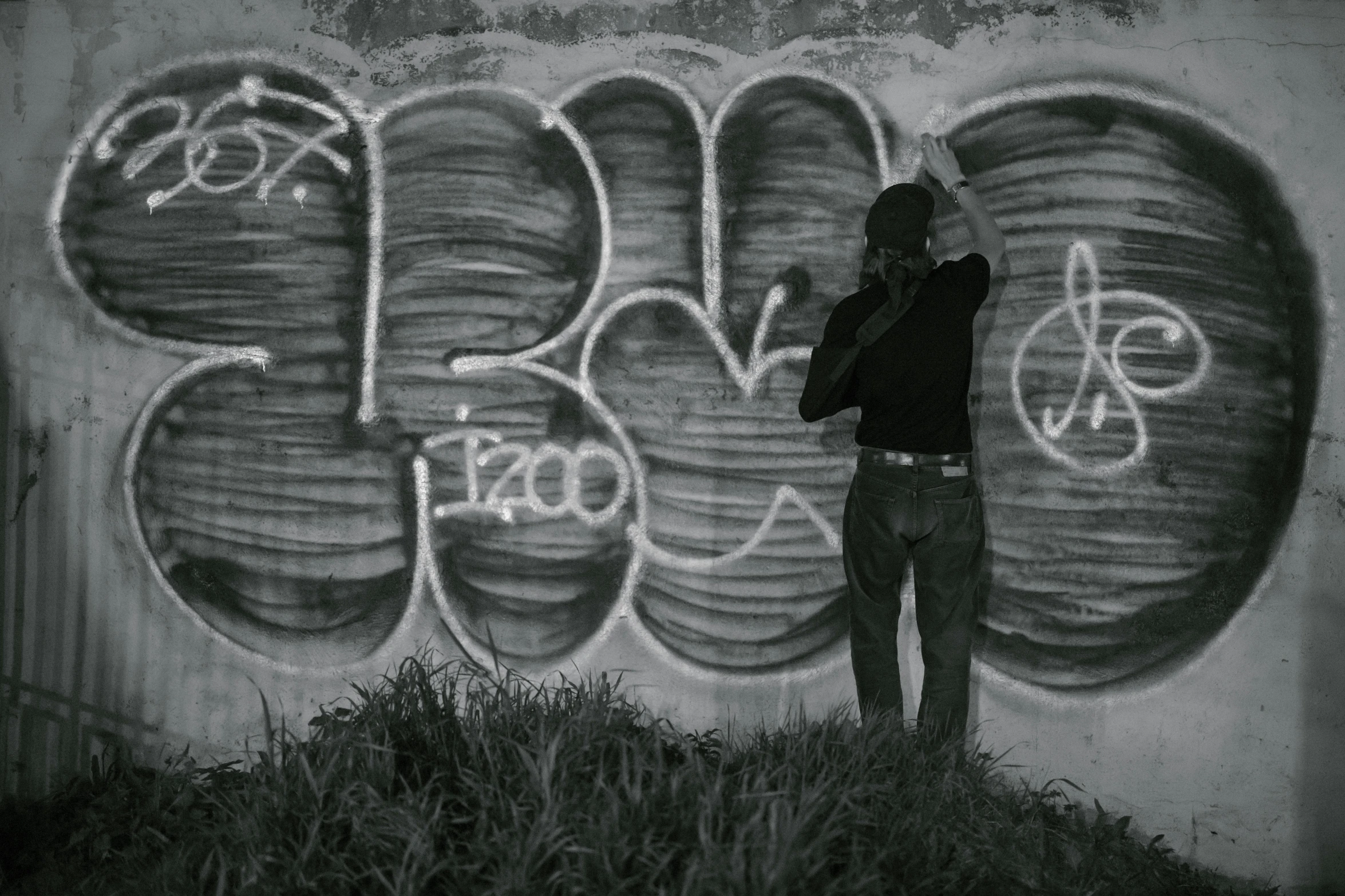 a man standing in front of a graffiti covered wall, graffiti, monochromatic photo, hunting, video, scratched photo