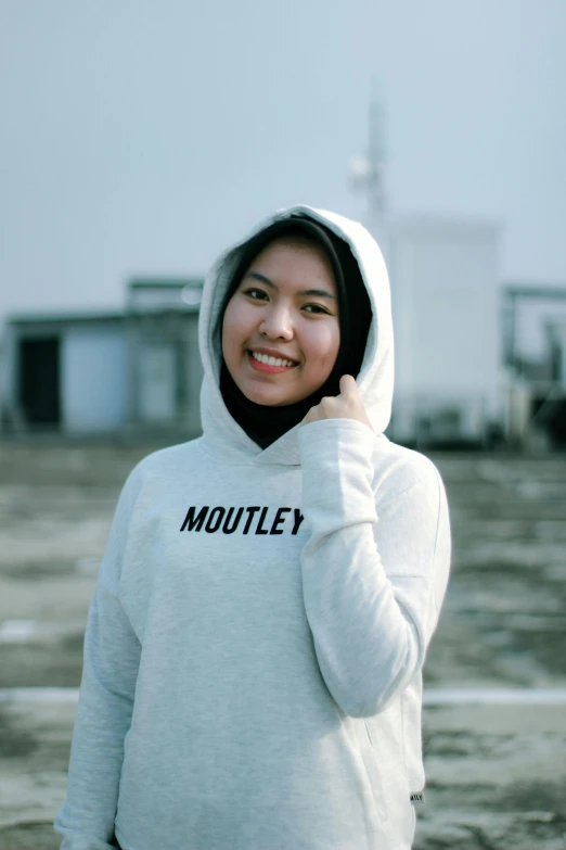 a woman in a hoodie talking on a cell phone, an album cover, by Robert Medley, pexels contest winner, hurufiyya, while smiling for a photograph, malaysian, ((portrait)), rooftop