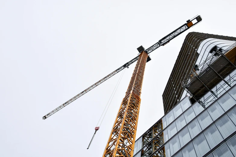 a crane standing on top of a building next to a tall building, viewed from the side, eeyrie, thumbnail, brown