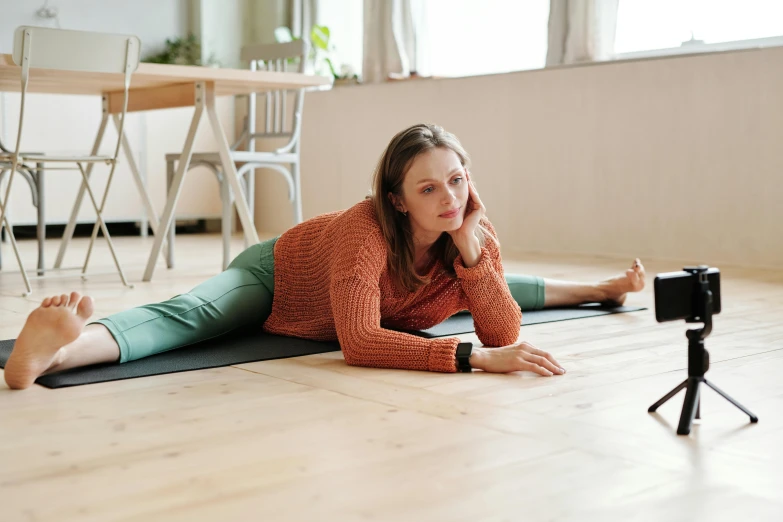 a woman laying on the floor next to a camera, unsplash, arabesque, doing splits and stretching, profile image, looking left, half image