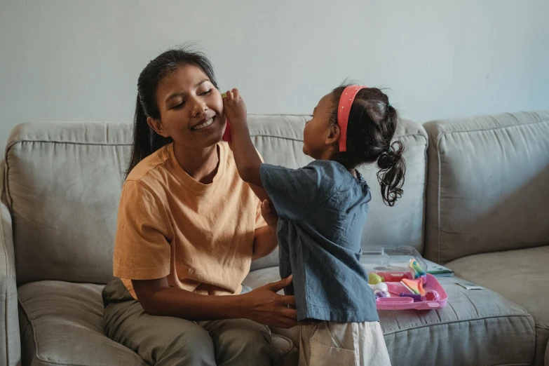 a woman and a little girl sitting on a couch, pexels contest winner, hurufiyya, earing a shirt laughing, avatar image, asian descent, face painting